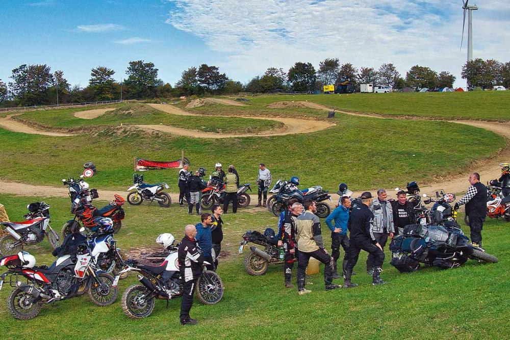 Motorradfahrer stehen in einer großen Gruppe auf einer Wiese beim ACT Camp